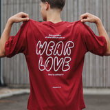Person wearing a red t-shirt with 'WEAR LOVE' text on the back, standing outdoors.
